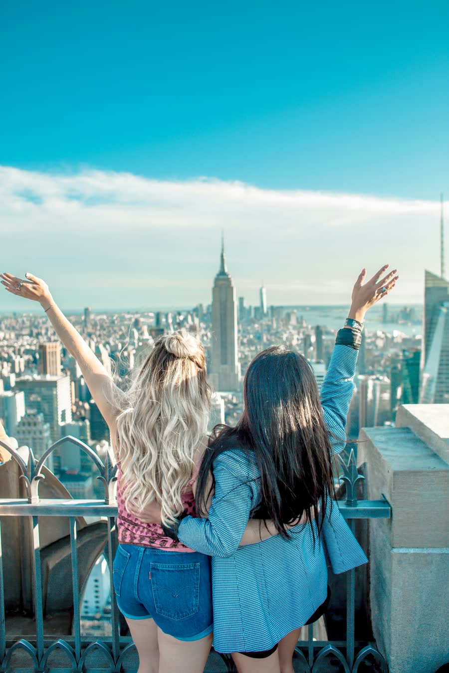 Two best friends over the city, arms in the air