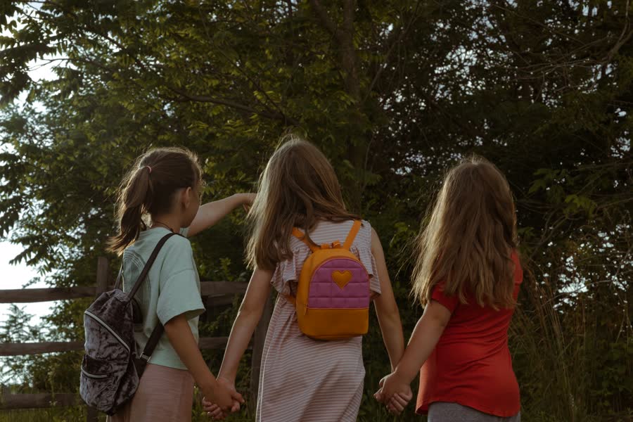 Three girls holding hands on the path home
