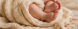 A newborn's feet wrapped in a knit blanket